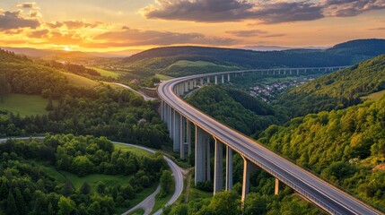 An overhead picture of a motorway bridge that connects towns at dusk, spanning a valley with verdant hills and forests as part of infrastructure development