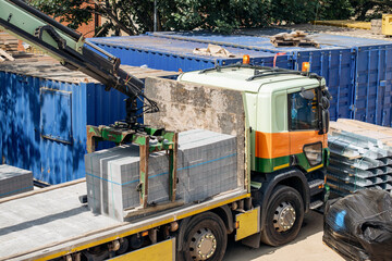 Construction Site by Warehouse With Truck Lifting Heavy Concrete Blocks During Day