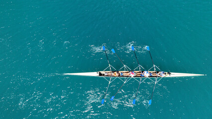 Aerial drone photo of sport canoe operated by team of young trained athletes in deep emerald sea