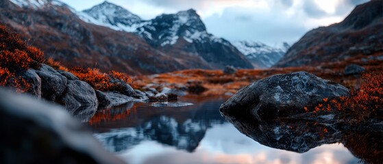  A foreground body of water lies before a mountain range with snow-capped peaks in the background