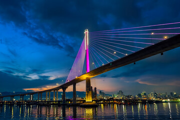 Cebu City, Philippines - CCLEX bridge illuminated at night, reflecting vibrant colors over the water.