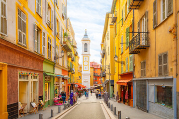 View of the campanile bell tower of the Nice Cathedral at Place Rossetti as tourists enjoy the narrow streets in the colorful Vieux Ville old town of Nice, France.