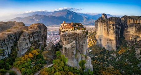Panoramic aerial sunrise view of the Meteora mountains with Agia Triada monastery situaded on a cliff high over the valley, Greece