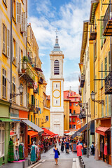 NICE, FRANCE: picturesque narrow streets of the old town, Vieux Nice, busy small shops and colorful facades of traditional houses, bell tower of Sainte Reparate church