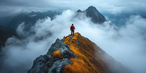 Solo hiker on mountain ridge above clouds at sunrise.