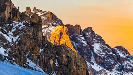 the illuminated peaks of snow-capped mountains in Italy. Dolomites in winter at sunset. Italian mountains under snow lit by the sun. Rocky mountains. Winter in the Dolomites