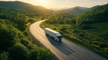 Aerial view of a modern electric truck driving on a scenic highway through green hills