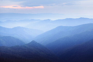 Misty blue mountains bathed in soft morning light. Peaceful and atmospheric nature photography