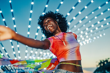 Young woman dancing and listening music with headphones at music festival