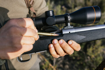 Hunter loading rifle with bullet in nature setting