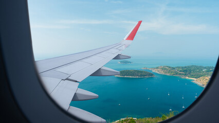 Airplane flying low over sea, view from plane window of plane wing and sky