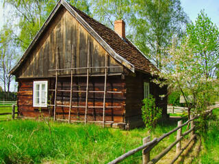 Stara drewniana chata w otoczeniu zieleni.