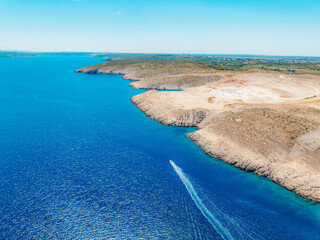 Vrsi near Zadar archipelago cove beach in stone desert scenery near Zecevo island, Dalmatia in Croatia and Pag Island in background. Boat trip