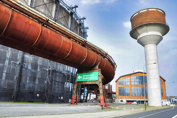 Dolní Vítkovice - Kompleks przemysłowy przekształcony w unikatowy ośrodek edukacyjny, kulturalny i społeczny. Duża konstrukcja przemysłowa z rdzawymi rurami i szklanymi ścianami.