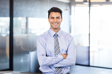Glass partitions dividing bright open office, overhead lights shining through frosted panels