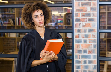 Orange hardcover book resting on wooden table under warm lights in library with glass partitions