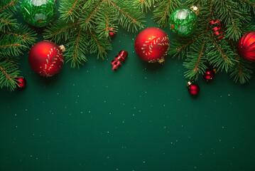 Merry Christmas and Happy Holidays greeting card, frame, banner. New Year. Noel. Golden and red Christmas ornaments on green background top view. Winter xmas holiday theme.