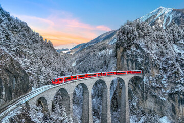 Aerial view of Train passing through famous mountain in Filisur, Switzerland. Landwasser Viaduct world heritage with train express in Swiss Alps snow winter scenery.
