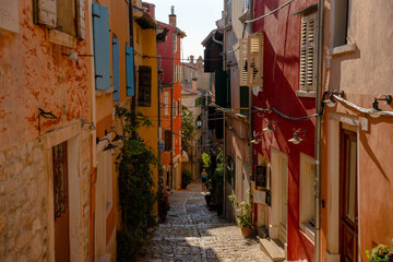 Rovinj, Croatia - August 15, 2025: Colorful Alley in Rovinj – a narrow cobblestone street lined with vivid red, orange, and yellow facades, wooden shutters, and hanging lamps in the old town.