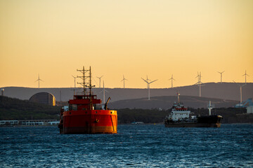 Cargo ships at sunset with wind turbines in the background