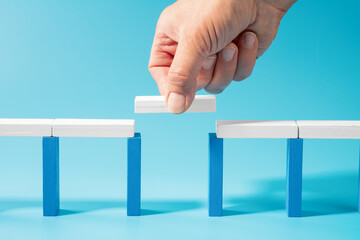 Hand builds a wooden toy bridge symbolizing trust and connection