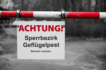 Schild mit der deutschen Aufschrift Sperrbezirk Geflügelpest, betreten verboten