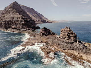 Aerial view of rugged volcanic cliffs and rock formations near Orzola, Lanzarote, surrounded by turquoise Atlantic waters. 