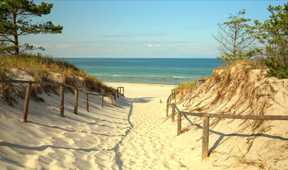 spokojny widok na wejście na piaszczystą plażę morską z szumiącym morzem w oddali