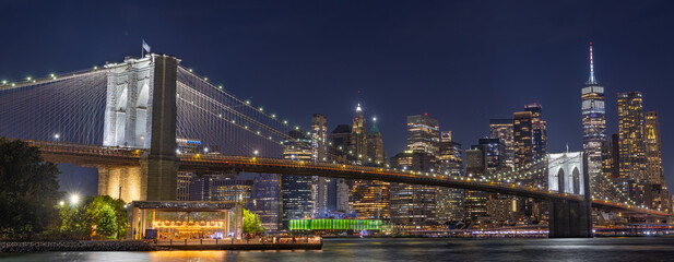 Panoramic view of the Brooklyn Bridge at night with the New York City skyline