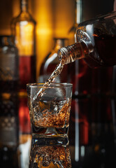 Pouring whiskey from a bottle into a glass.
