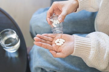 Sick asian young woman, girl holding tablet pill on hand pouring drug from medication bottle, painkiller medicine from stomach pain, head ache, pain for treatment, take drug or vitamin, health care.