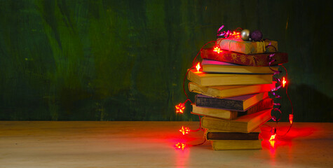 giving books for christmas,christmas gift,present,reading,literature,education, christmas,holiday concept with heap of books, christmas lights and decoration