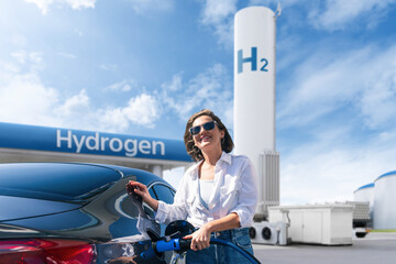 Woman holds a hydrogen fueling nozzle on a hydrogen filling station. Refueling car with hydrogen fuel
