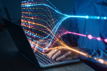 Programmer typing on laptop with colorful data flow visualization, concept of artificial intelligence, big data analysis, machine learning, and digital technology innovation