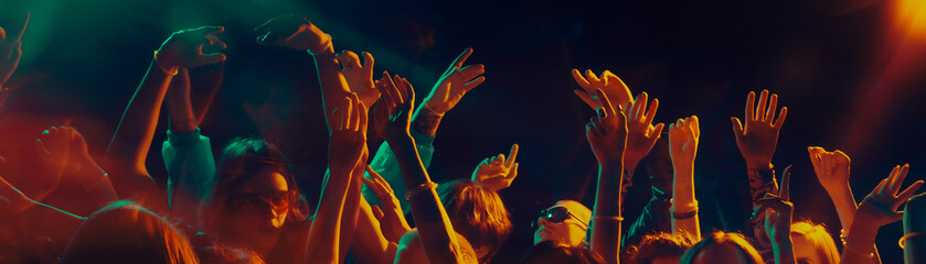 Dancing crowd silhouettes under dramatic concert lighting. Concept of shared emotions, rhythmic movement, social connection, music immersion and Christmas night celebration atmosphere. Banner