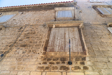 Stare zabytkowe kamienice i uliczki w mieście Trogir w Chorwacji z pięknymi oknami i okiennicami. 