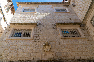 Stare zabytkowe kamienice i uliczki w mieście Trogir w Chorwacji z pięknymi oknami i okiennicami. 