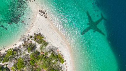 Aerial view of shadow passenger plane silhouette and sandy beach blue sea with waves at sea beach summer vacation sea travel concept 