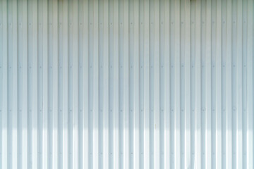 White corrugated metal wall background texture with vertical lines and rivets. Clean industrial surface for construction or architectural backdrop. Frontal view with bright natural light.