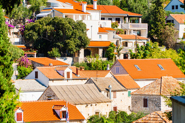Miasto Maslinica na wyspie Solta w Chorwacji. Tradycyjna zabudowa i wąskie uliczki. Domy z czerwoną dachówką.