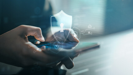 A close-up of hands using a smartphone with a glowing security shield icon, symbolizing mobile cybersecurity, data protection, privacy safety, secure access, encryption, and digital security.