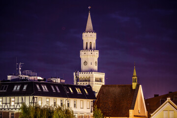 Oświetlona wieża ratusza w Opolu nocą, widok na zabytkową architekturę rynku na tle ciemnego nieba