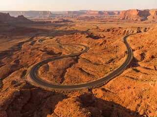 Aerial View Of A Winding Asphalt Road Cutting Through A Red Rock Desert Landscape