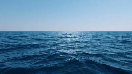 A tranquil vast expanse of deep blue ocean meets the clear blue sky at the infinite horizon