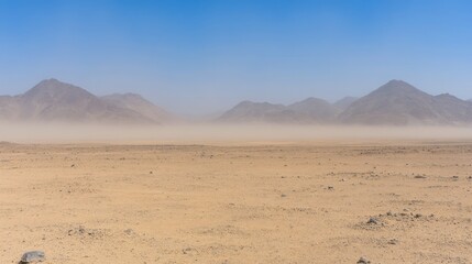 Dust particles creating a hazy veil over an arid desert landscape with mountains in the distance