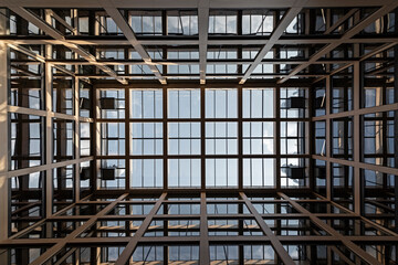 Nowoczesny szklany sufit w budynku biurowym z geometryczną konstrukcją widok z dołu na niebo