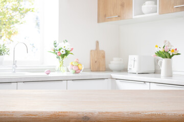Bleached wooden table top on interior background of blurred kitchen counter decorated for Easter
