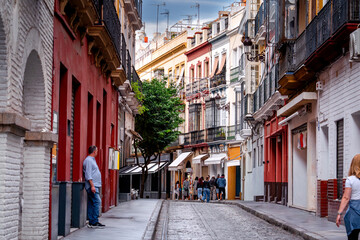 Narrow street in Seville with people, cafes, and restaurants, Spain, everyday life on streets Andalusia.