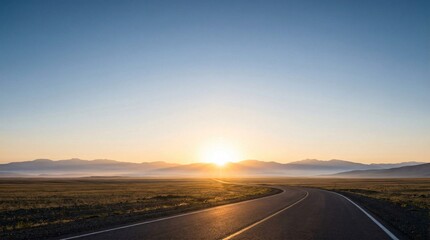 A winding asphalt road leads across a vast open landscape towards a bright sunrise over distant mountains