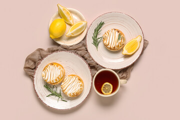 Plates with delicious lemon tarts and cup of tea on beige background